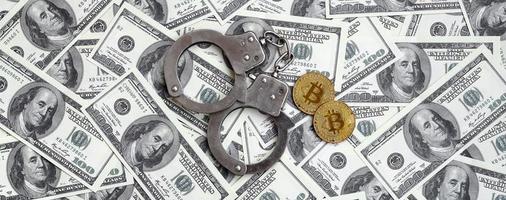las esposas de la policía y los bitcoins se encuentran en una gran cantidad de billetes de un dólar. el concepto de problemas con la ley durante la minería ilegal de criptomonedas y las operaciones de bitcoin foto