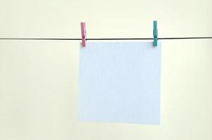 White blank cards on rope, light wall background. Creative reminder, small sheets of paper on old clothespin, memo backdrop photo