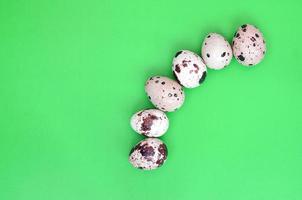 Quail eggs on a light green surface, top view, empty place for t photo