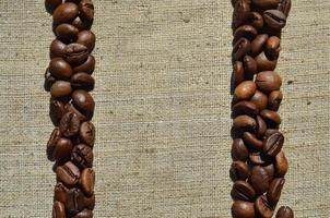 Texture of a gray canvas made of old and coarse burlap with coffee beans on it photo