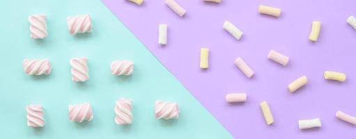 Colorful marshmallow laid out on violet and blue paper background. pastel creative textured pattern. minimal photo