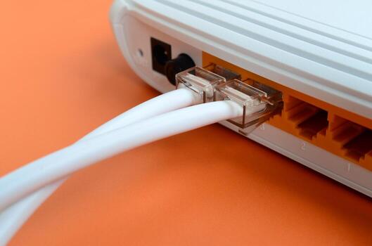 The Internet cable plugs are connected to the Internet router, which lies on a bright orange background. Items required for Internet connection photo