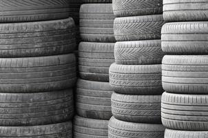 Old used tires stacked with high piles in secondary car parts shop garage photo