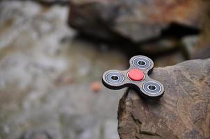 The wooden spinner lies on the rocks against the background of a small waterfall and a river photo