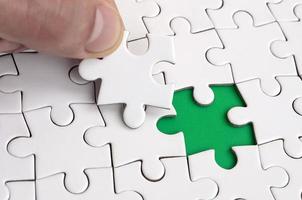 The human hand fills the last missing elements of the surface from the jigsaw puzzle. The concept of the completion of the initiated cases photo