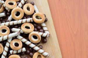 túbulos crujientes, bolas de chocolate y bagels yacen sobre una superficie de madera. mezcla de varios dulces foto