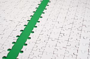 The green path is laid on the platform of a white folded jigsaw puzzle. Texture image with copy space for text photo