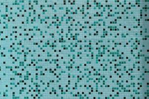 The texture of the wall, decorated with a mosaic of various small square tiles. Abstract pattern of ceramic tiles on the wall photo