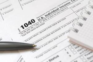 The pen and notebook is lies on the tax form 1040 U.S. Individual Income Tax Return. The time to pay taxes photo