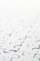 Close up of a white jigsaw puzzle in assembled state in perspective. Many components of a large whole mosaic are united photo