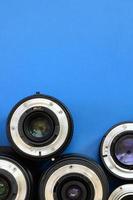 Several photographic lenses lie on a bright blue background. Space for text photo