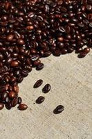 Texture of a gray canvas made of old and coarse burlap with coffee beans on it photo