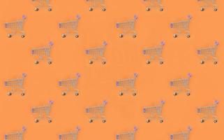 Shopping addiction, shopping lover or shopaholic concept. Many small empty shopping carts perform a pattern on a pastel colored paper background. Flat lay composition, top view photo