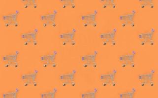 Shopping addiction, shopping lover or shopaholic concept. Many small empty shopping carts perform a pattern on a pastel colored paper background. Flat lay composition, top view photo