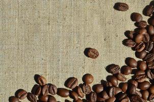 Texture of a gray canvas made of old and coarse burlap with coffee beans on it photo