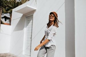Short-haired girl in stylish trousers and white shirt walks. Portrait of woman in sunglasses in yar photo