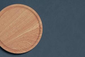 Round cutting board top view on dark background with empty space. photo