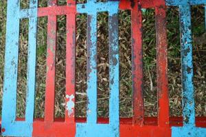 iron trellis with red and blue paint that has peeled off photo