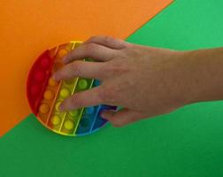 Pop it toy on a green and orange background, a person's hand photo