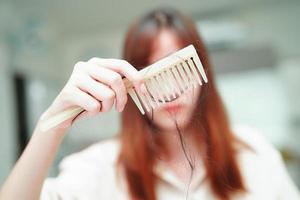 Asian woman have problem with long hair loss attach to comb brush. photo