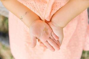 A cross on a chain on the palms of the girl who was baptized photo