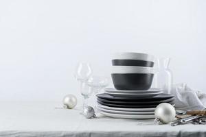 Set of black and white tableware with plates, cutlery and glasses with holiday decorations on dining table, copy space photo