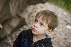 un niño en el fondo de una montaña rocosa mira algo con curiosidad y se sorprende. naturaleza, rocas, montañas. foto