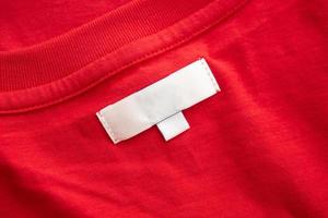 White blank clothing tag label on new red cotton shirt fabric texture background photo