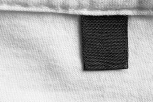 Black blank laundry care clothes label on white cotton shirt background photo