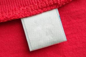 etiqueta de ropa blanca en blanco para el cuidado de la ropa en el fondo de la camisa de algodón rojo foto