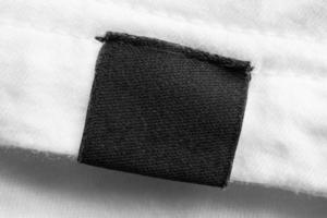 etiqueta de ropa negra en blanco para el cuidado de la ropa en el fondo de la camisa de algodón blanco foto