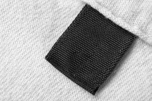 etiqueta de ropa negra en blanco para el cuidado de la ropa en el fondo de la camisa de algodón blanco foto