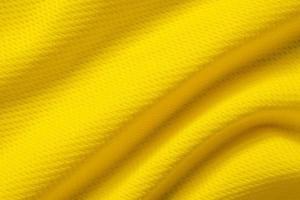 Yellow sports clothing fabric football shirt jersey texture close up photo