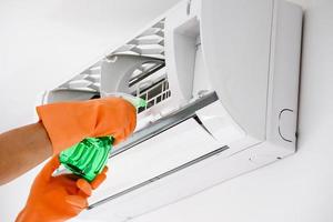 Asian man cleaning air conditioner with spray bottle photo