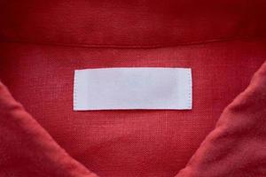 White blank clothing tag label on red linen shirt fabric texture background photo