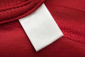 etiqueta de ropa blanca en blanco para el cuidado de la ropa en el fondo de la camisa deportiva de poliéster rojo foto