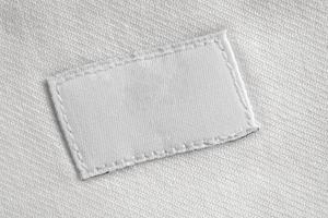 White blank laundry care clothes label on cotton shirt background photo