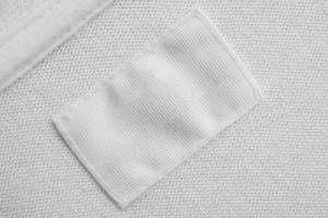 White blank laundry care clothes label on cotton shirt background photo