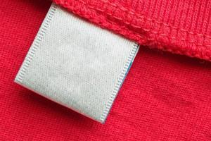 etiqueta de ropa blanca en blanco para el cuidado de la ropa en el fondo de la camisa de algodón rojo foto