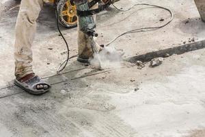 Construction worker using jackhammer drilling concrete surface photo