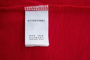 White laundry care washing instructions clothes label on red cotton shirt photo