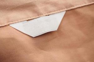 blank white clothing label on brown fabric texture background photo