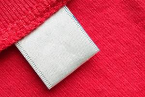 White blank laundry care clothes label on red cotton shirt background photo