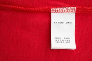 White laundry care washing instructions clothes label on red cotton shirt photo