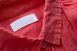 etiqueta de ropa blanca en blanco sobre fondo de textura de tela de camisa de lino rojo foto