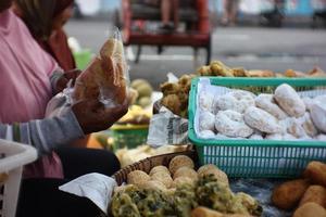 People sell and buy various traditional cakes and various fried foods photo