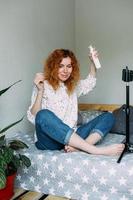 Red haired woman blogger broadcasts live reviews of beauty products for hair photo