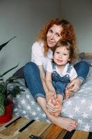 Young mother and child have fun and fool around at home on the bed photo