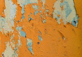 grunge texture of an old wall with peeling bright orange paint photo