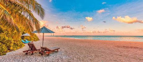 Beautiful panoramic nature. Tropical beach sunset as summer island landscape with chairs umbrella palm leaves calm sea shore, coast. Luxury travel panoramic destination banner for vacation or holiday photo